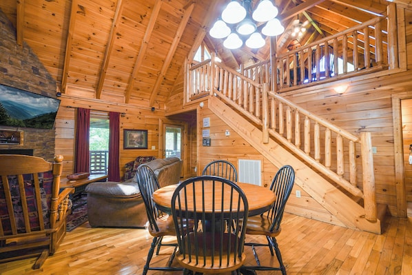 A wooden interior with a dining area, a staircase, and a view of the outdoors. - A Time to Remember -Private Hot Tub • Game Room • Resort Pools (Sevierville)