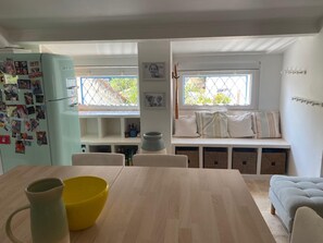 Ett kök med en inbyggd bänk, ett matbord med stolar och ett kylskåp som är dekorerat med fotografier.