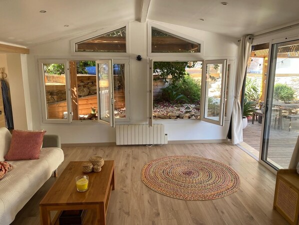 A modern living room with a sofa, coffee table, and a large window offering a view of a garden. - Cozy 3BR Apt w/ AC Cassis (Cassis)