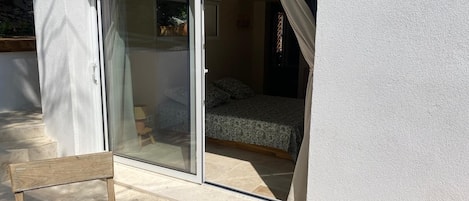 Ein Zimmer mit einem Bett, einer Schiebetür und einem kleinen Holzsessel.
