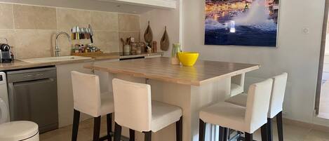 Una cocina moderna con una isla central, taburetes de bar y una zona de comedor.