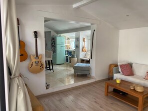 A living room with a wooden coffee table, a white sofa, and a guitar on the wall. - Cozy 3BR Apt w/ AC Cassis (Cassis)
