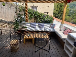 Eine Holzterrasse mit einer Couch, Sesseln und einem Tisch.