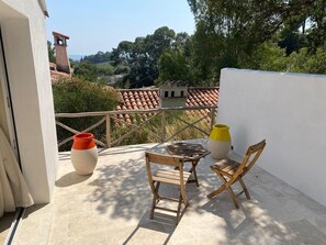 A balcony with a table and chairs, a potted plant, and a view of the surrounding landscape. - Cozy 3BR Apt w/ AC Cassis (Cassis)