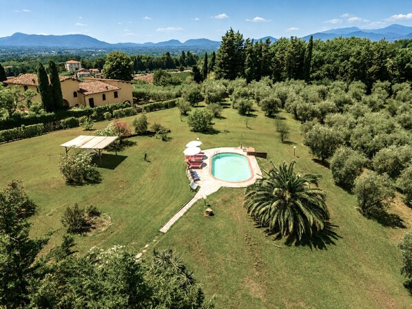A residential property with a swimming pool, a garden, and a view of the surrounding countryside.