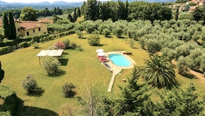 A residential property with a swimming pool, lush greenery, and a view of distant mountains. - Gaetano Spadaro Estate, La Rosa Room (Capannori)