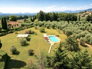 Une propriété résidentielle dotée d’une piscine, d’une végétation luxuriante et offrant une vue sur les montagnes lointaines.