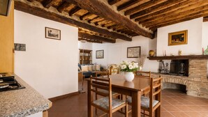 A rustic interior with a wooden dining table, chairs, a fireplace, and a tiled floor. - Gaetano Spadaro Estate, Leccino Apartment (Capannori)