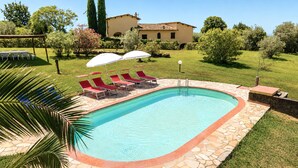 A swimming pool with lounge chairs and umbrellas, surrounded by a stone deck and a grassy lawn. - Gaetano Spadaro Estate, Leccino Apartment (Capannori)