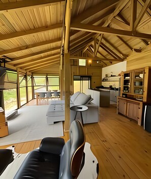 A spacious living area with a high ceiling, a sofa, a dining table, and a kitchen area.