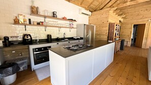 A modern kitchen with a central island, built-in oven, and a wooden interior.