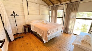 A room with a bed, a chair, a small table, and a coat rack.