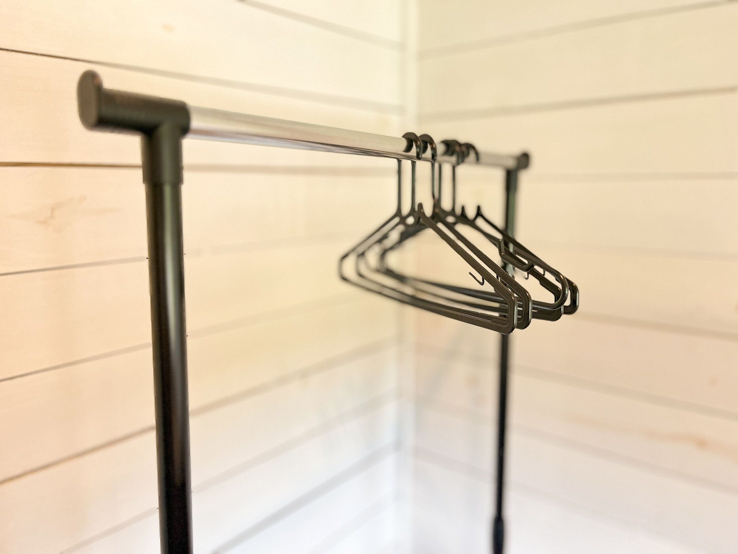 Un étendoir métallique fixé au mur, avec des vêtements suspendus, et dont les lignes sont horizontales.