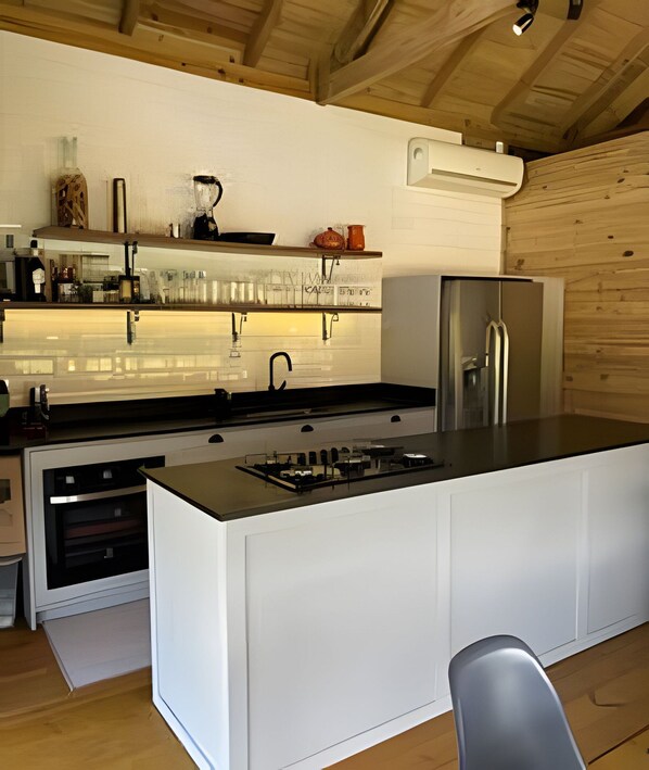 A modern kitchen with a central island, built-in appliances, and wooden ceiling beams.