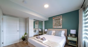 Une chambre d’hôtel comprenant un lit, des tables de chevet, un miroir et une œuvre d’art accrochée au mur.