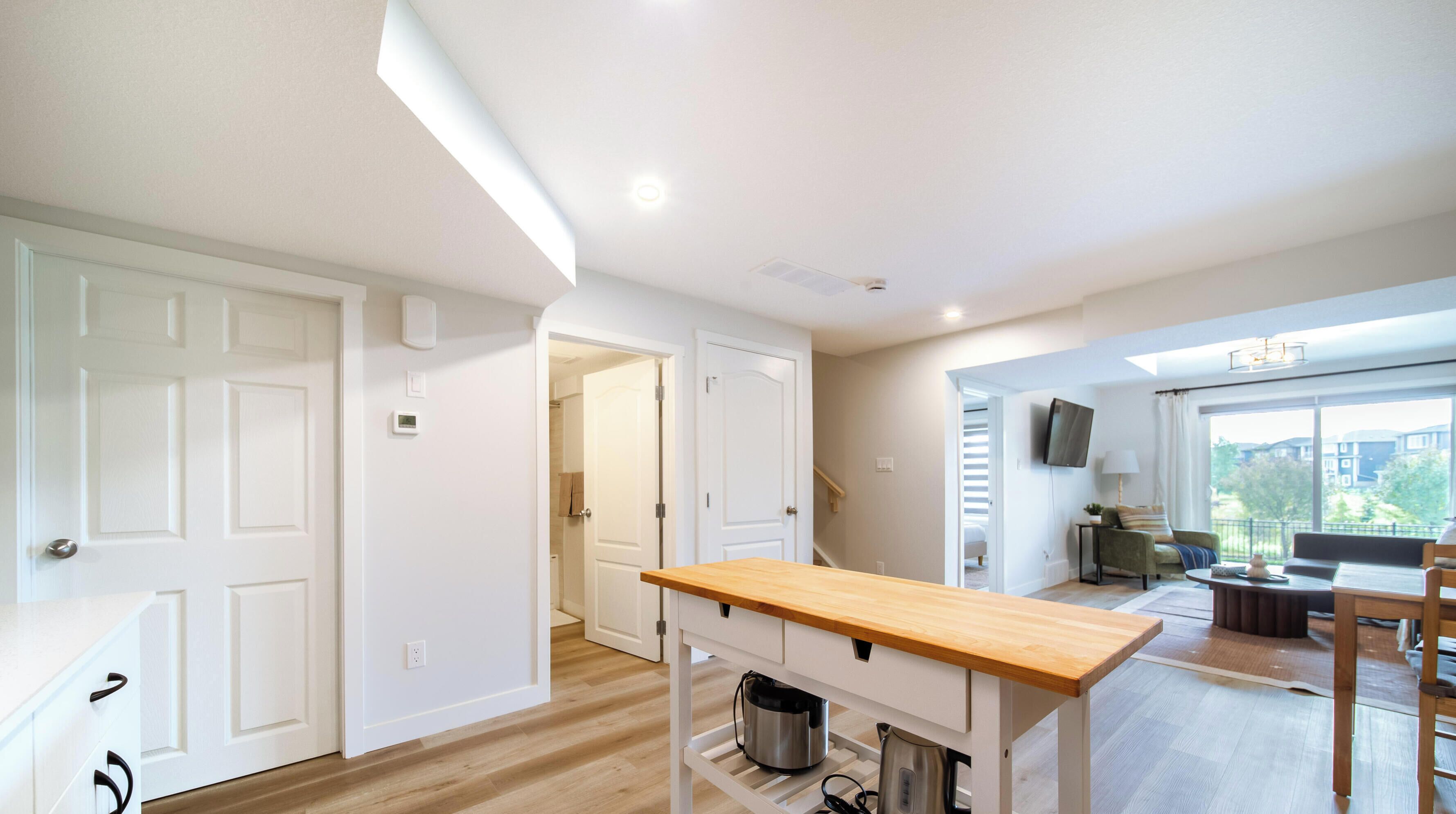 Une cuisine moderne avec un plan de travail en bois, une bouilloire en acier inoxydable et un meuble blanc.