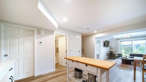 Une cuisine moderne avec un plan de travail en bois, une bouilloire en acier inoxydable et un meuble blanc.