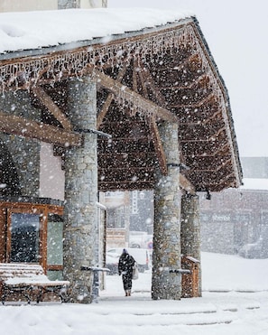 A stone building with a wooden roof and a bench outside. - “V16” by Versant Collection (Val Thorens)