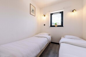 A small, clean room with two single beds, a window with a view, and a wall-mounted light fixture. - Residence Altineige, Ski In-Out with WiFi in Val Thorens, “V8” by Versant Collection (Val Thorens)
