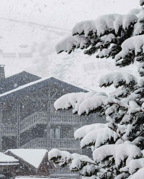 A building with snow-covered roofs and trees, indicating a winter setting. - Residence Altineige, Ski In-Out with WiFi in Val Thorens, “V8” by Versant Collection (Val Thorens)