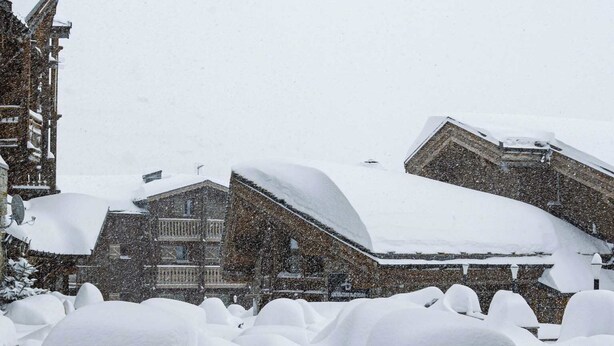 Ein Gebäude mit schnee bedecktem, geneigten Dach, umgeben von verschneitem Gelände.