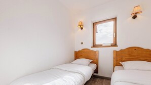 Et lille, rent værelse med to enkeltsenge, et vindue og væglamper.