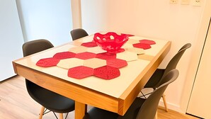Een eettafel met een tafelkleed met geometrische patronen en een rode decoratie.