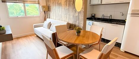 Una cocina moderna con armarios blancos, una mesa de comedor de madera y un sofá en la sala.