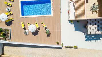 Un espace piscine aménagé sur le toit, avec des chaises longues, des parasols et un coin salon comprenant des tables et des chaises.