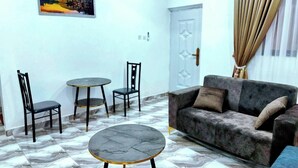 A room with a sofa, two chairs, a small round table, and a picture on the wall. - Legon hills hotel and suits (Adenta)
