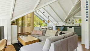 A spacious living area with a high ceiling, a sofa set, a coffee table, and a television. - Holiday home with garden and wildlife in Gjern (Truust)