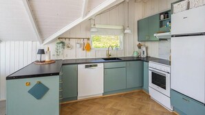 A kitchen with a wooden herringbone floor, white and teal cabinetry, a white refrigerator, and a window with a view of greenery. - Holiday home with garden and wildlife in Gjern (Truust)