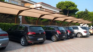 Un aparcamiento con varios coches, una marquesina y un edificio de fachada de ladrillo.