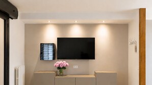 Una sala de estar moderna con un televisor de pantalla plana montado en la pared, un banco empotrado con espacio de almacenamiento y un radiador en la pared.