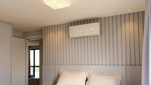 A hotel room with a bed, an air conditioning unit, a wardrobe, and a window with curtains. - ASA Coral Sea Gravata 2BR (Navegantes)