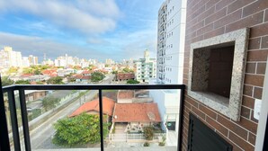 A balcony with a view of a cityscape, including residential buildings and a brick wall. - ASA Coral Sea Gravata 2BR (Navegantes)
