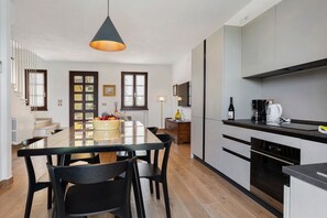 A modern kitchen with a glass dining table, black chairs, and a pendant light. - Holiday Home 'Katy Lake Timo' with Wi-Fi and Air Conditioning (Chiodi II)