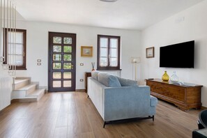 Un salon moderne avec un canapé, un téléviseur et un meuble en bois.