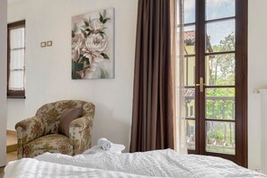 A bedroom with a bed, a chair, a painting, and a window with curtains. - Holiday Home 'Katy Lake Timo' with Wi-Fi and Air Conditioning (Chiodi II)