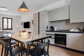 Eine moderne Küche mit Essbereich, ausgestattet mit einer Kaffeemaschine, einer Weinflasche und einem Fernseher an der Wand.