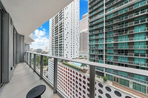 Ein Balkon mit Blick auf hohe Gebäude, einen Pool und eine Wand mit Muster.