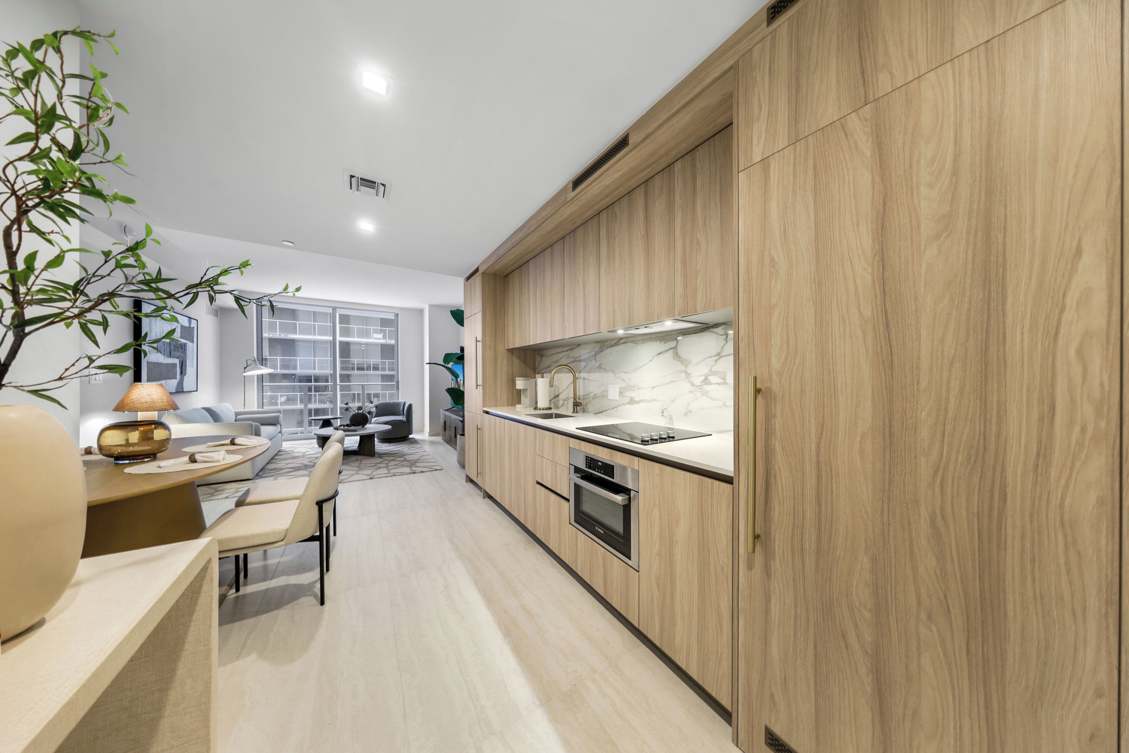 Eine moderne Küche mit Holzausstattung, integriertem Backofen und einer Marmorarbeitsplatte.
