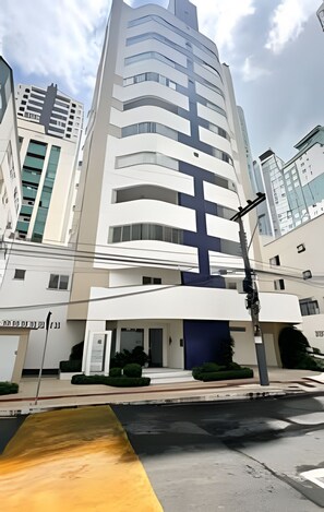 Un bâtiment moderne doté d’un élément vertical marquant, d’une entrée sécurisée par un portail et surplombant un ciel dégagé.