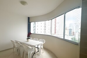 A room with a curved balcony, a white table, and four white chairs. - ASA Apto Praia Central Amplo 2QT BC (Balneário Camboriú)