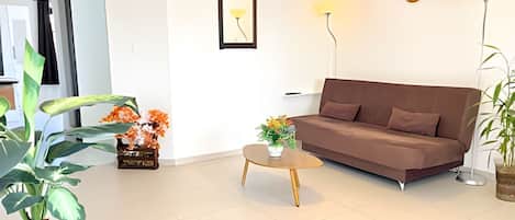Una sala de estar moderna con un sofá marrón, una mesita redonda y una planta en maceta.