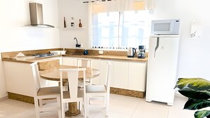 Una cocina moderna con una isla central, armarios blancos, un microondas y una cafetera.