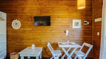 A cozy wooden cabin interior with a television, framed artwork, and a table set for dining.