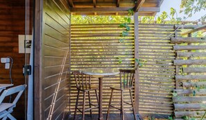 A wooden outdoor seating area with a table and chairs, a wooden fence, and a wooden door. - Charming and Well-equipped Chalet Rel0002 (Imbituba)