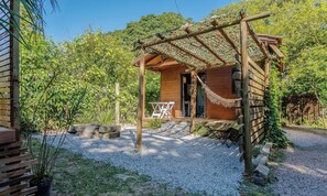 A wooden cabin with a porch, surrounded by gravel and greenery. - Complete Chalet in Imbituba Rel0001 (Imbituba)