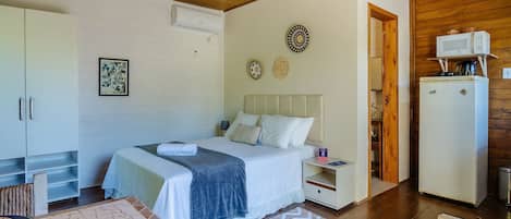 A bedroom with a bed, bedside table, wardrobe, and a kitchenette.